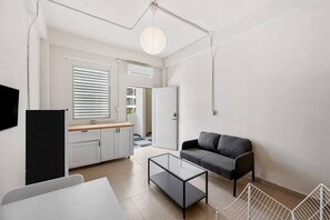 Un salon moderne avec une table basse en verre, un canapé et un téléviseur.