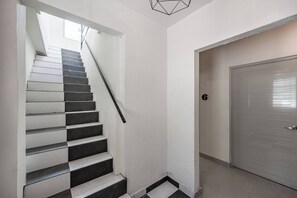 A staircase with alternating black and white steps, a door with the number 6, and a geometric light fixture. - Barrio Sanctuary - Encanto (San Juan city)