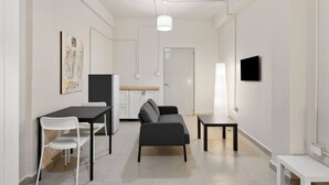 Ein modernes Wohnzimmer mit Sofa, Esstisch, Stühlen, Fernseher und Kunstwerken an der Wand.