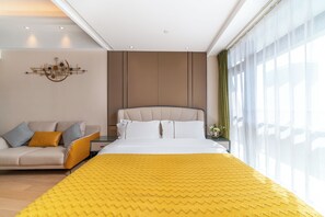Une chambre d’hôtel moderne équipée d’un lit, d’un canapé, d’une table de chevet et d’un luminaire fixé au mur.