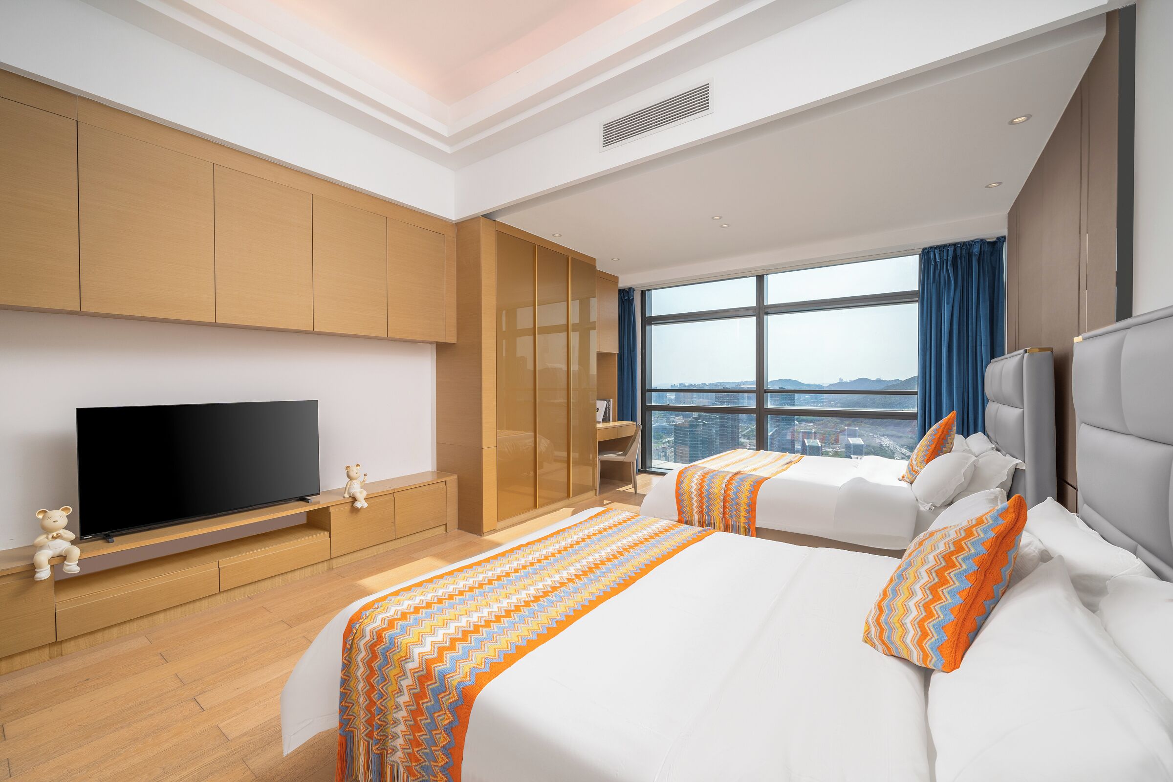 A modern hotel room with a large bed, a television, and a city view.