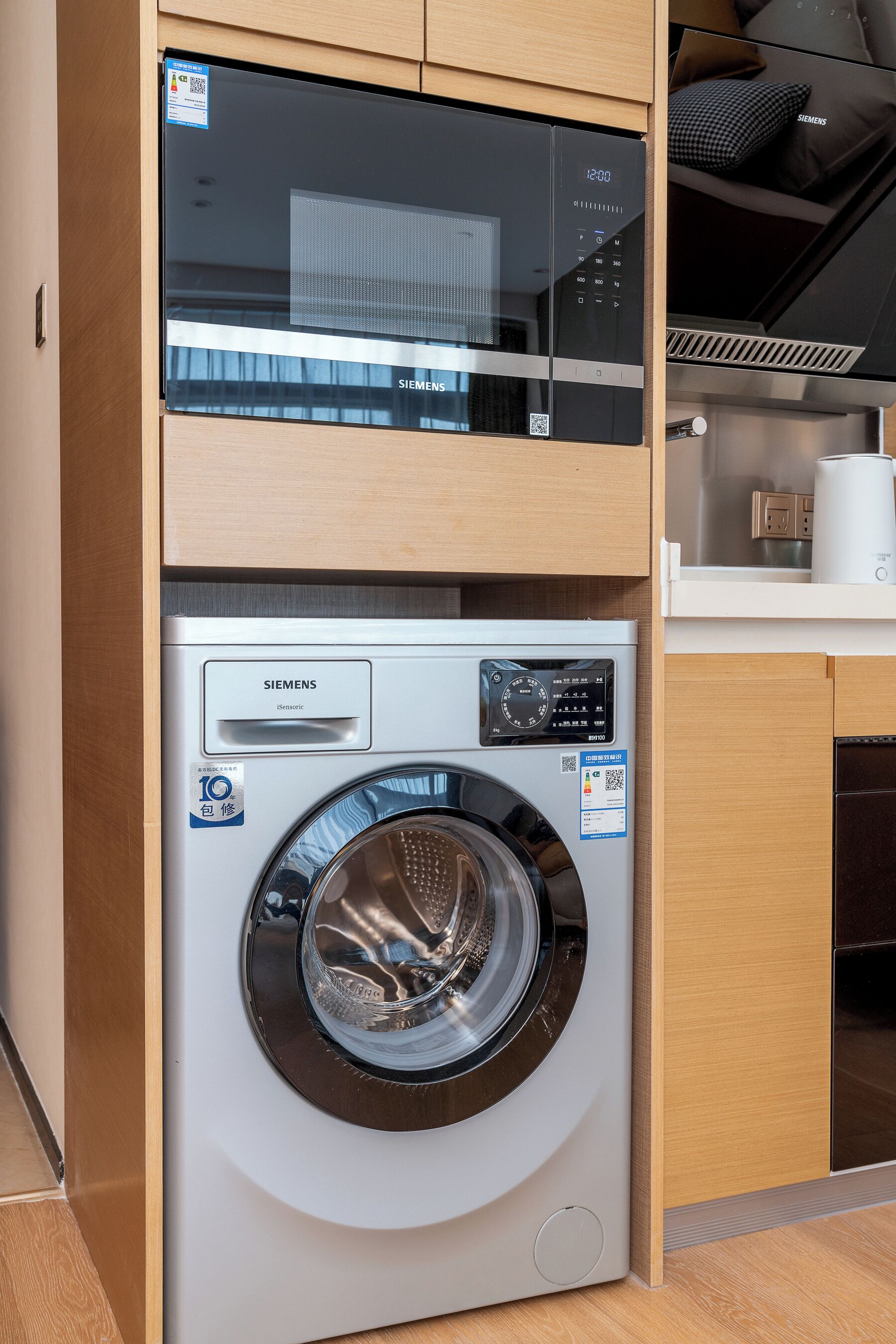 A modern kitchen with a Siemens microwave, a Siemens washing machine, and wooden cabinetry.