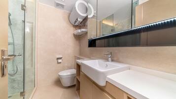 A modern bathroom with a glass shower enclosure, a white toilet, and a large mirror above a white sink.