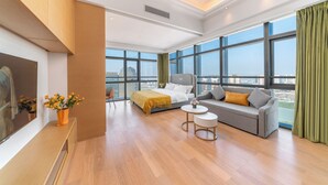 Una habitación de hotel moderna con una cama grande, un sofá, una mesita y un televisor.