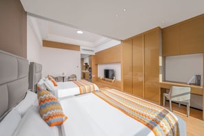 Habitación de hotel con dos camas, un escritorio, un televisor y una kitchenette.