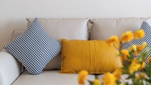 Una sala de estar moderna con un sofá, cojines estampados y una pieza decorativa en la pared.