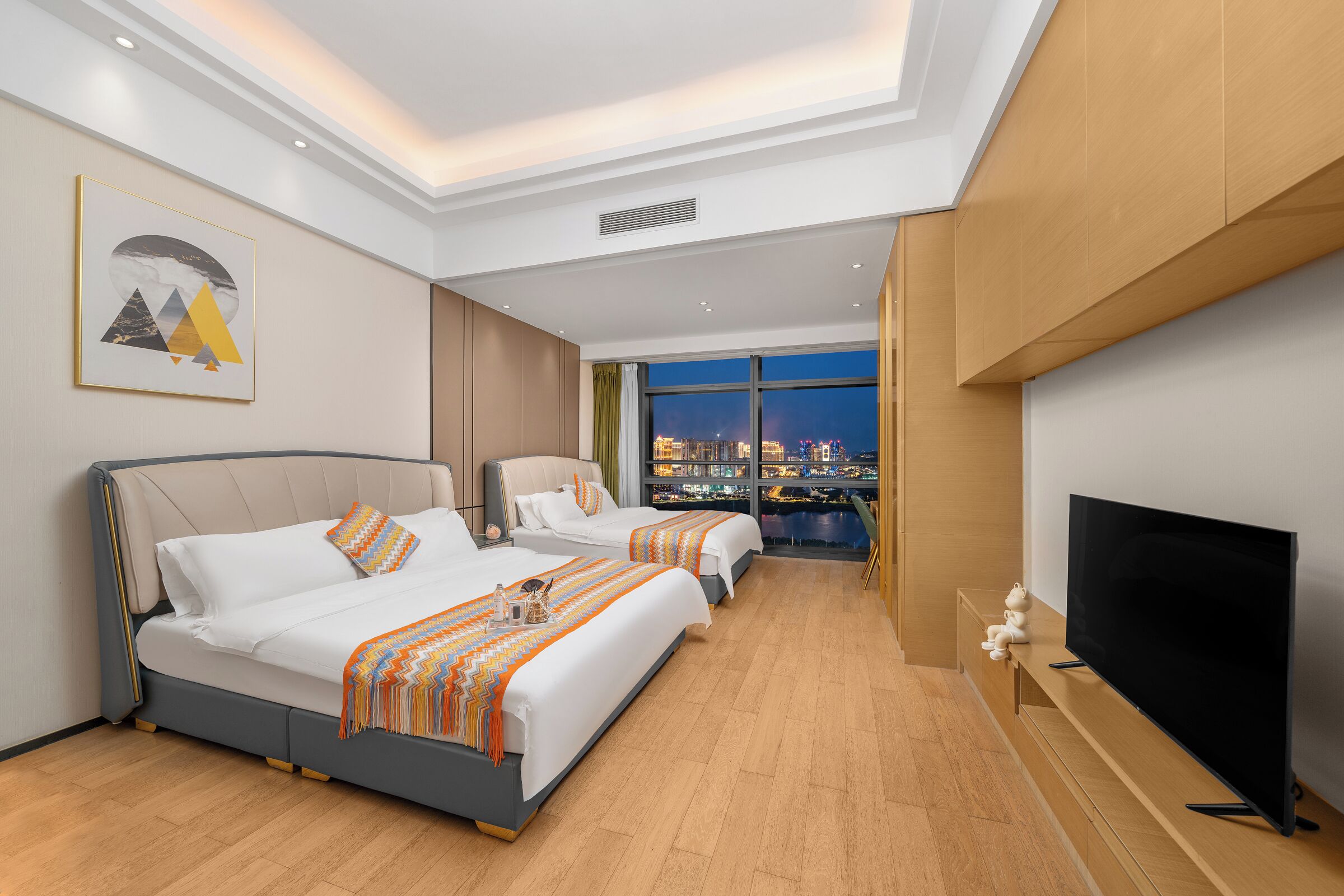 A hotel room with two beds, a television, and a city view.