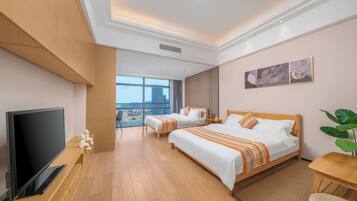 A hotel room with a TV, two beds, a large window, and a city view.