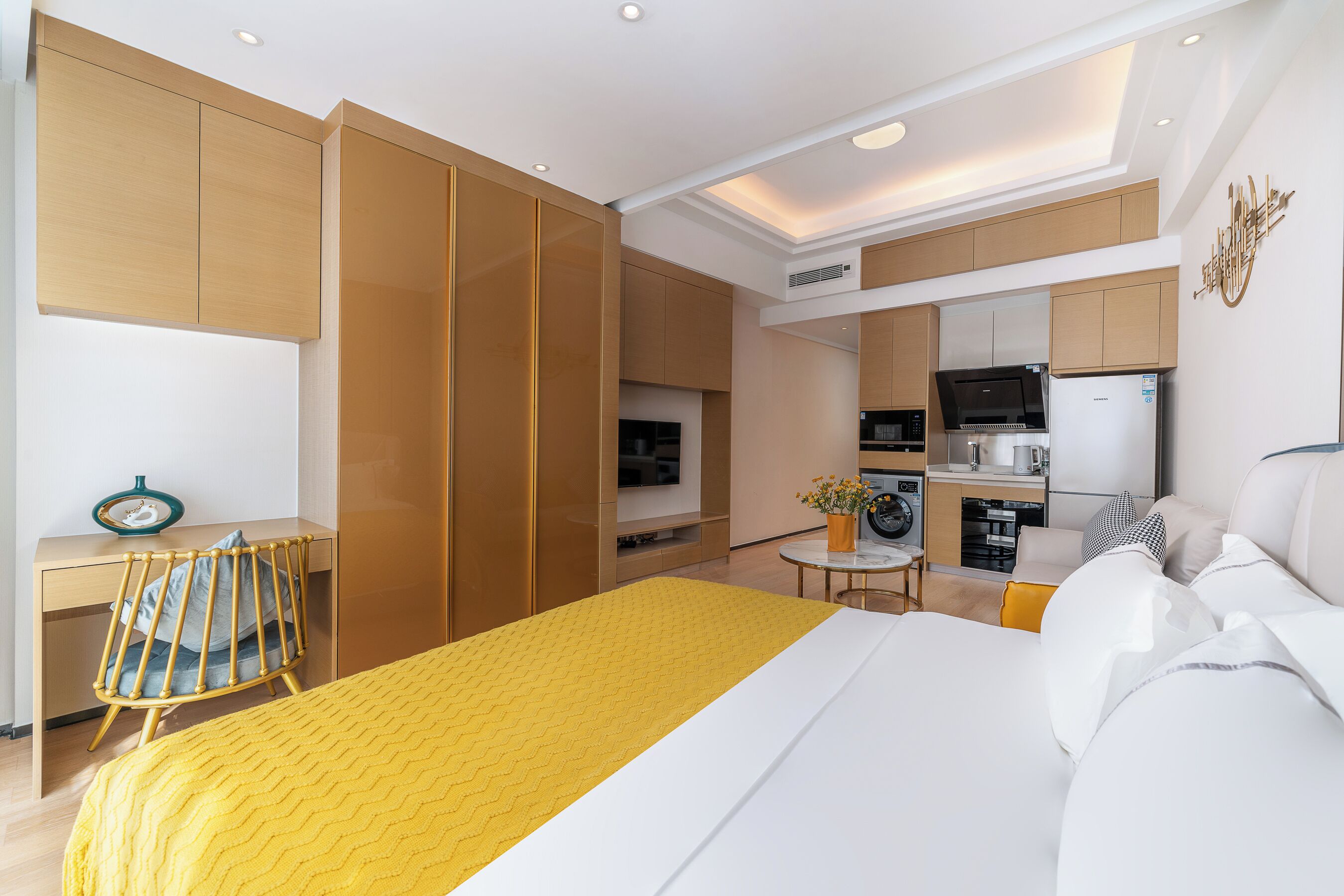 Una habitación de hotel moderna con cama, escritorio, silla, kitchenette y baño.