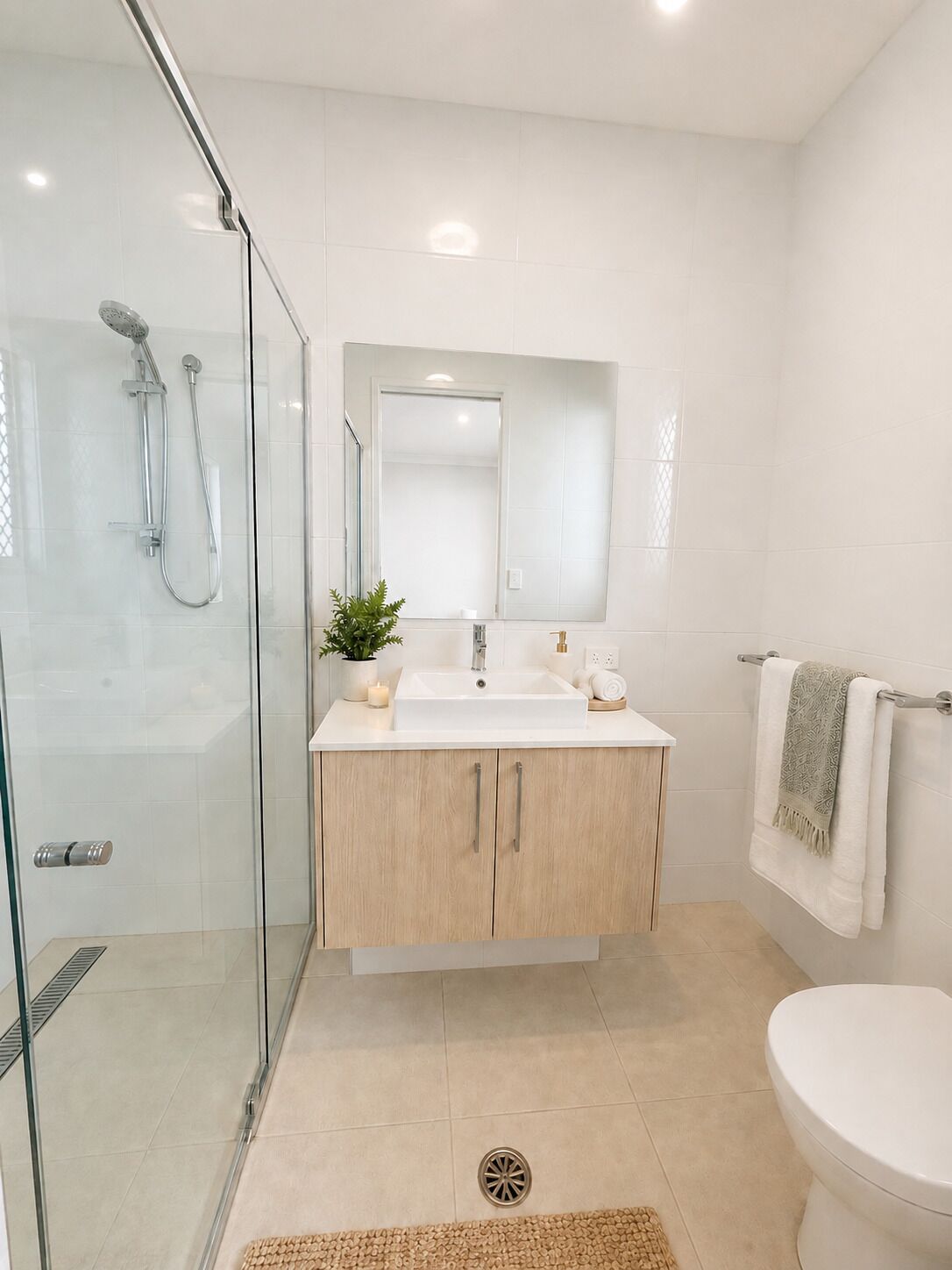 A modern bathroom with a glass shower enclosure, a sink with a mirror, and a toilet.