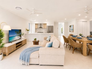 A modern living room with a sofa, TV, dining table, and chairs.