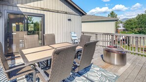 Eine Terrasse im Freien mit Esstisch, Stühlen, Grill und Glastür zu einem Innenbereich.