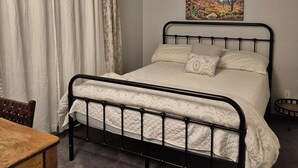Een slaapkamer met een bed, een schilderij, een tafel en een stoel.