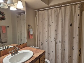 Une salle de bain équipée d’un lavabo, d’un miroir, d’un porte-serviettes et d’un rideau de douche à motifs.