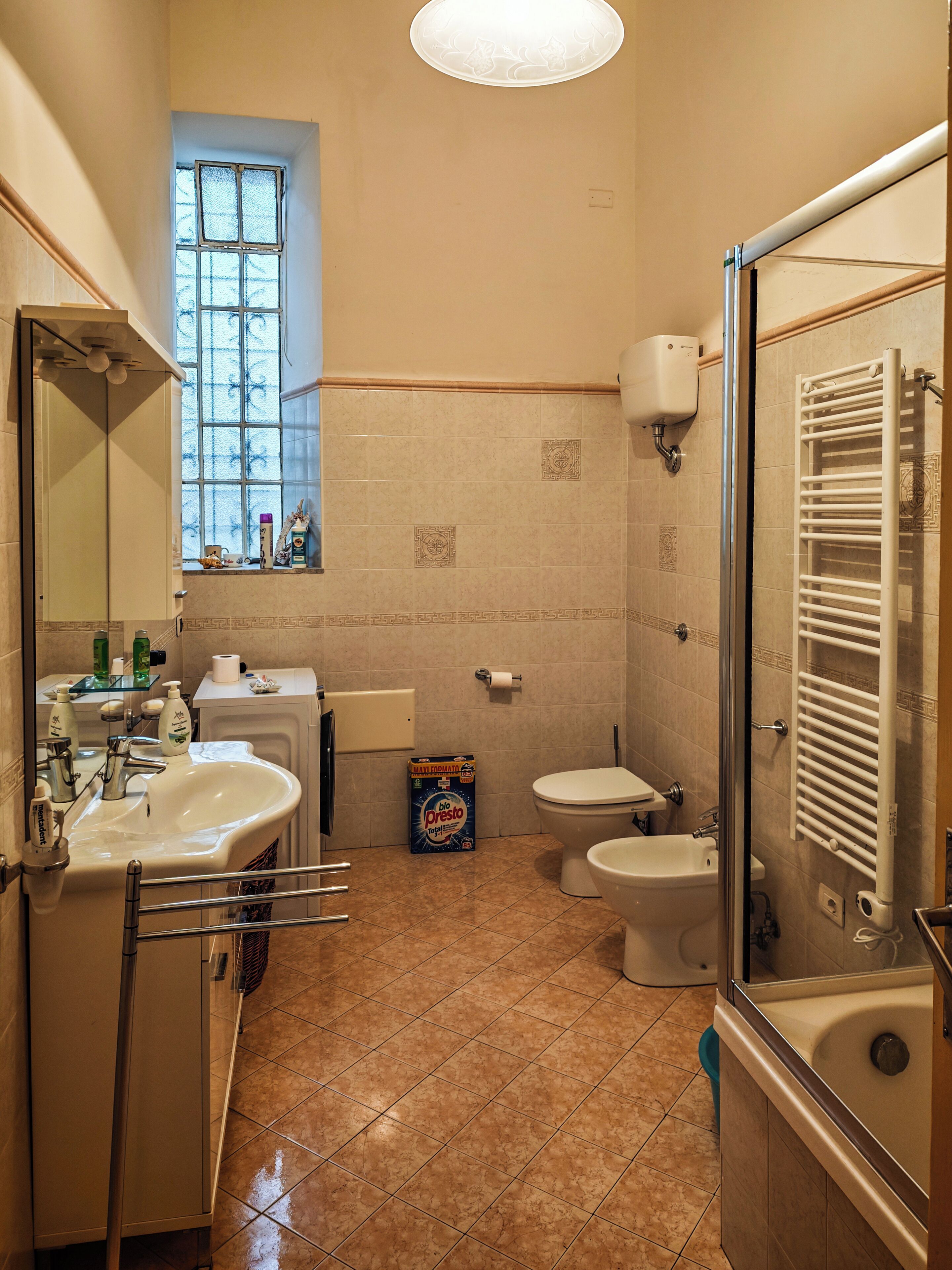 A bathroom with a sink, toilet, and bathtub, a window, and a shower area.