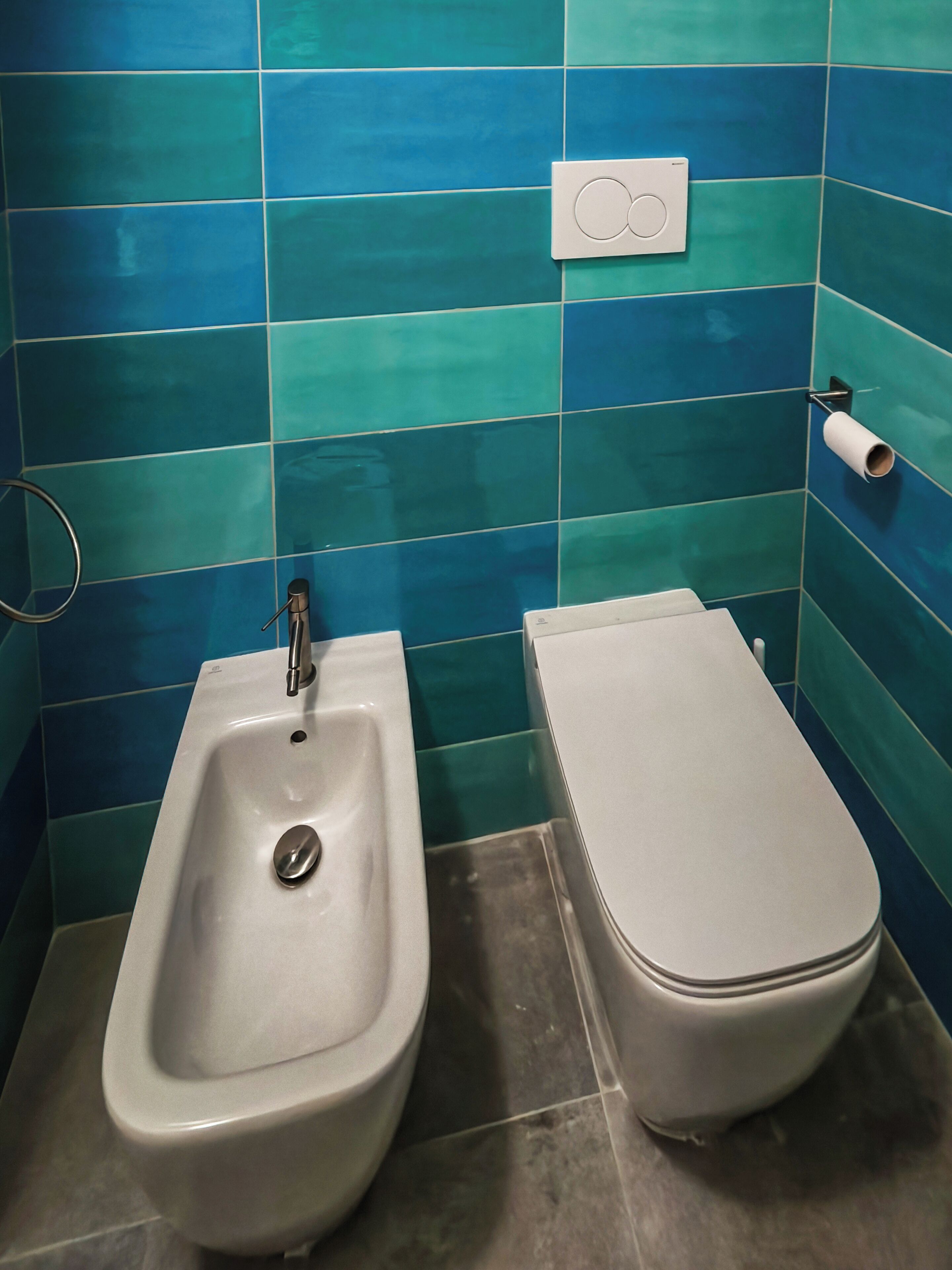 Un baño con orinal, inodoro y dispensador de toallas.