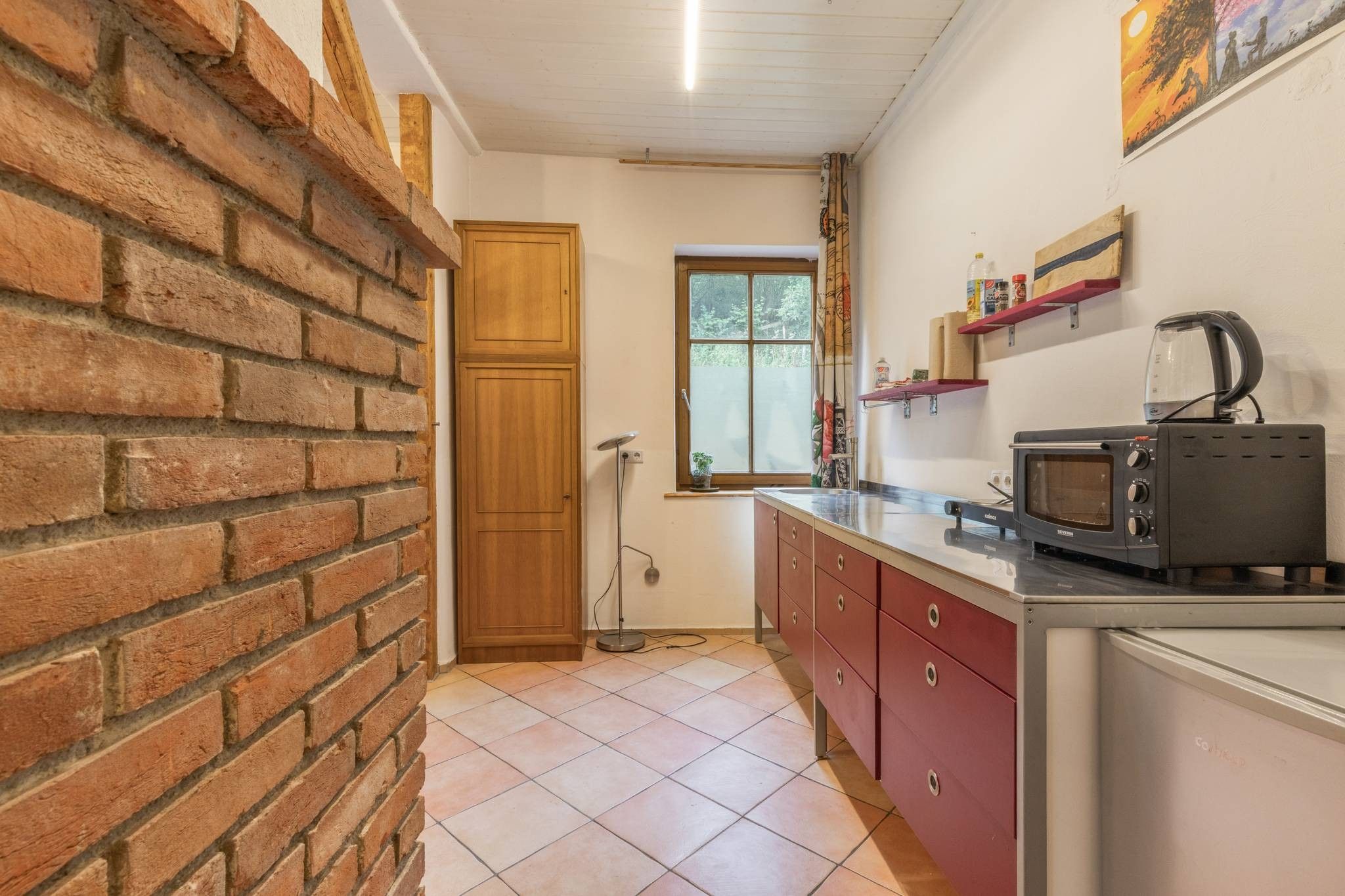 Eine Küche mit Backsteinwand, Holztür und Fenster.