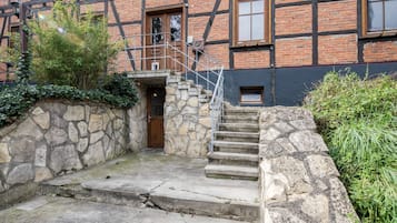 A stone staircase leading to a wooden door, with a brick building in the background.