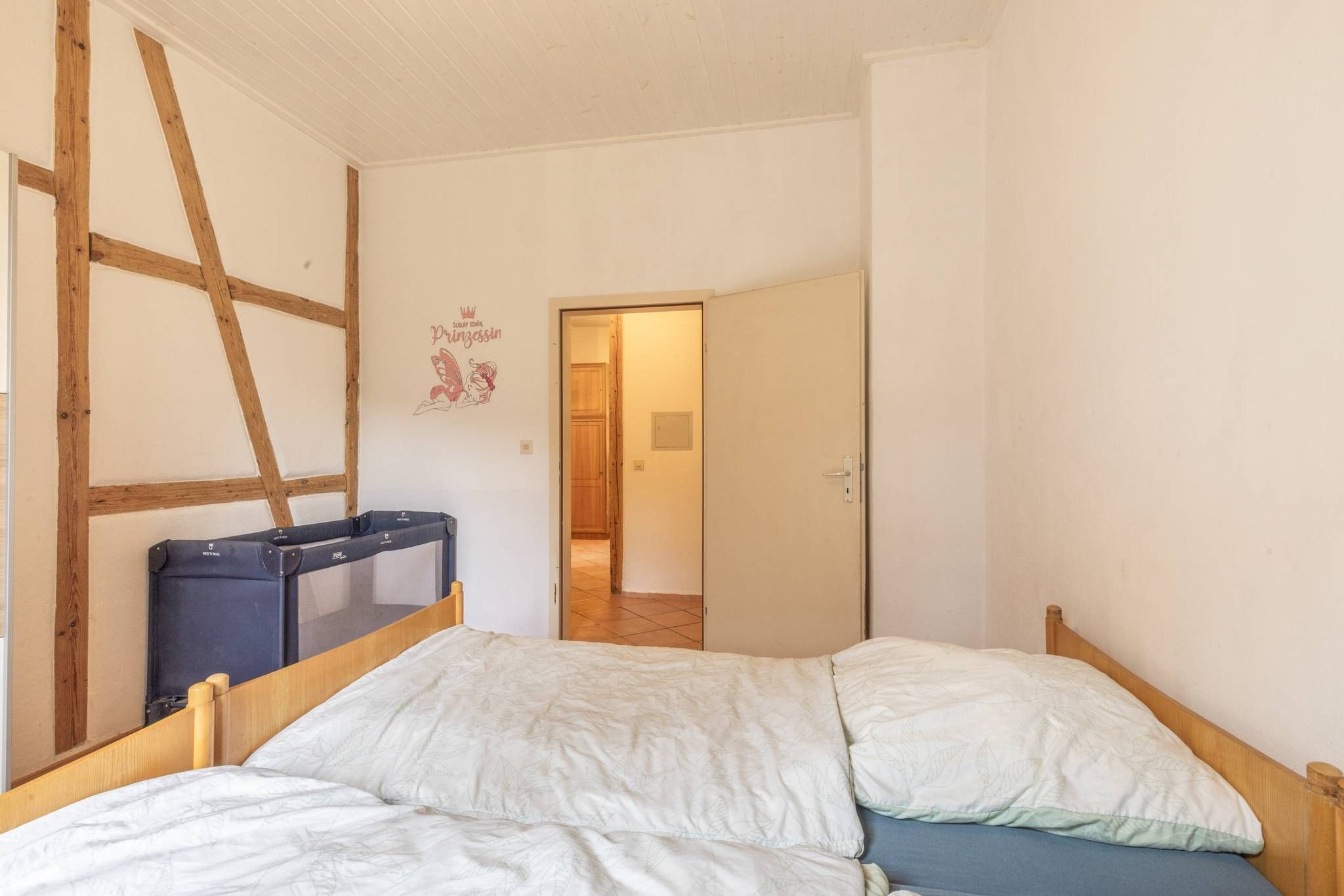 Un dormitorio con cama, armario y puerta que da a otra habitación.