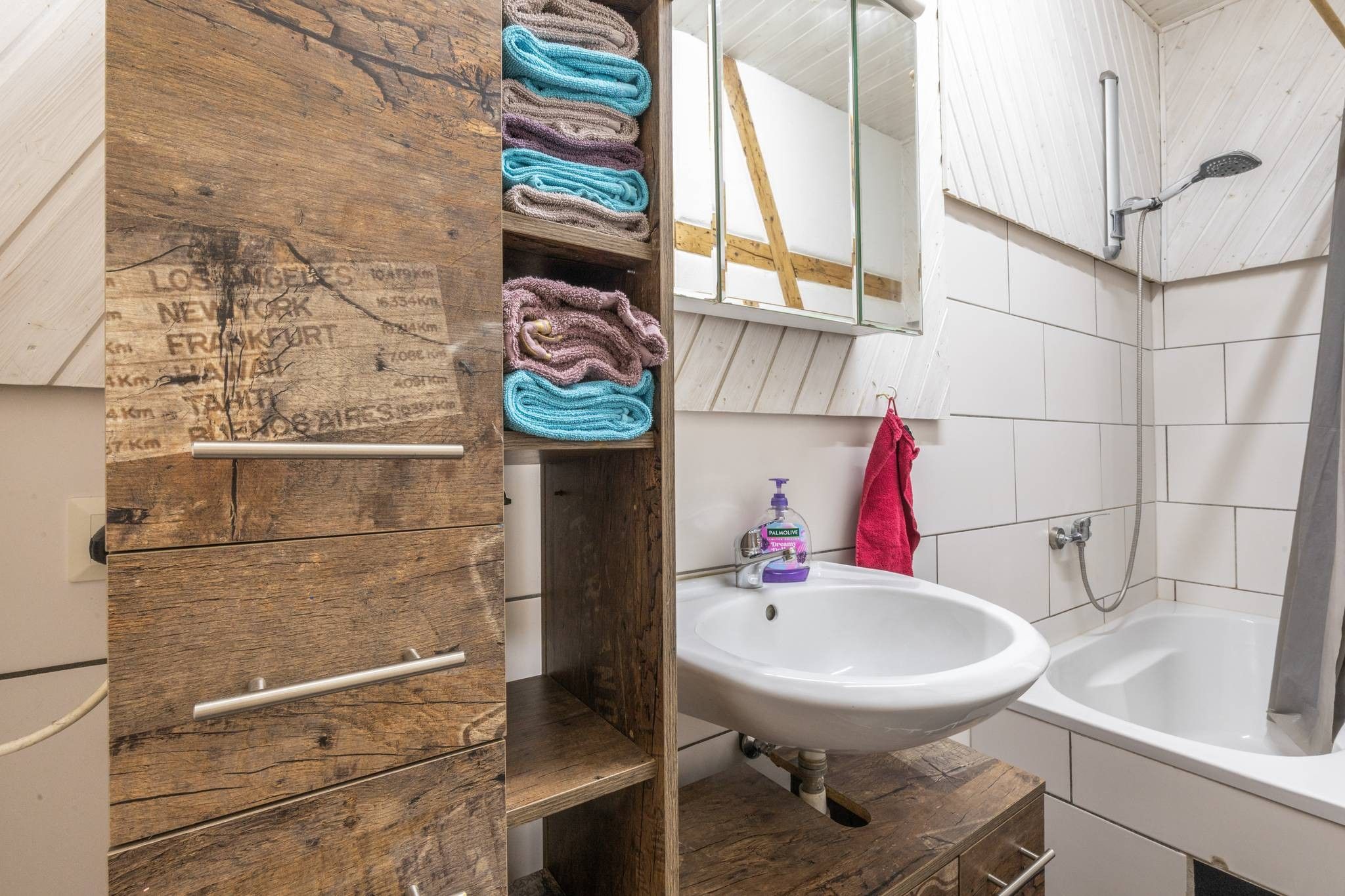 Une salle de bain avec un meuble-lavabo en bois, un évier et une baignoire.