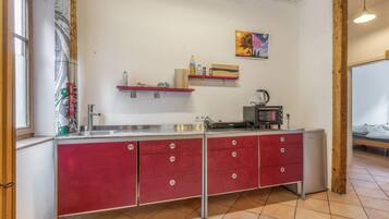 A compact kitchen with a red cabinet, a coffee maker, and a microwave.