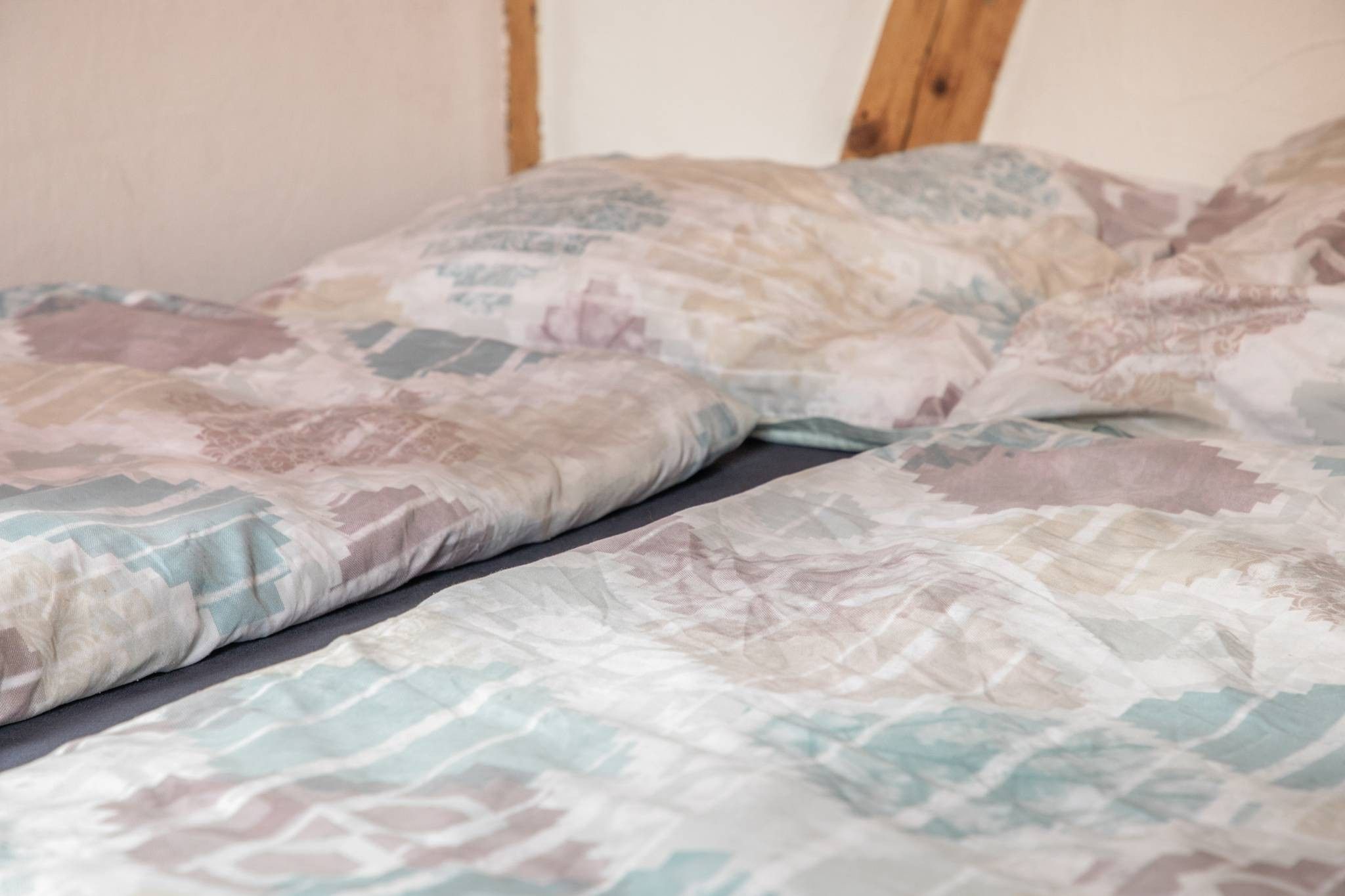 A bed with a patterned bedspread and pillows.