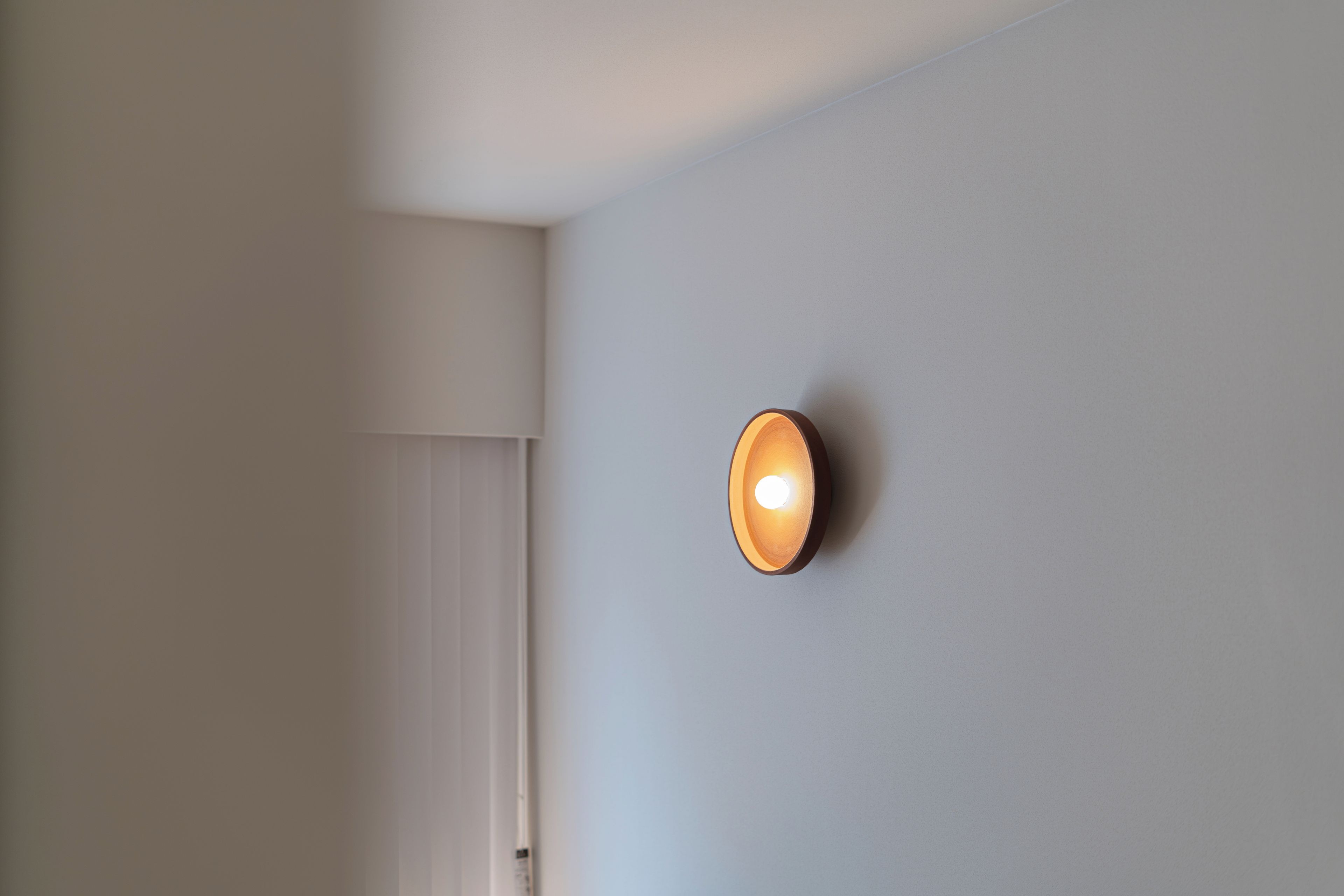 A wall-mounted light fixture in a room with white walls and a door.