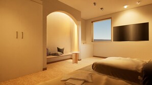 A modern bedroom with a bed, a small table, a bench, and a TV mounted on the wall. - Giraffe Nakasu haku (Fukuoka)