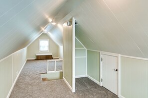 Een kamer met een schuine kap, een raam, een inbouwbank en een deur.