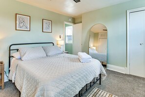 Een slaapkamer met een bed, nachtlampjes, een deur en een spiegel.
