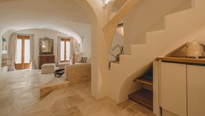 Ein großzügiger Innenraum mit hoher Decke, einer Treppe und einer Küchenzeile.