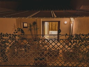 A room with a bed, a window, and a door. There is a plant in the corner and a chair near the window. - Elite Collection - Olea: The Secret Roof (Olbia)