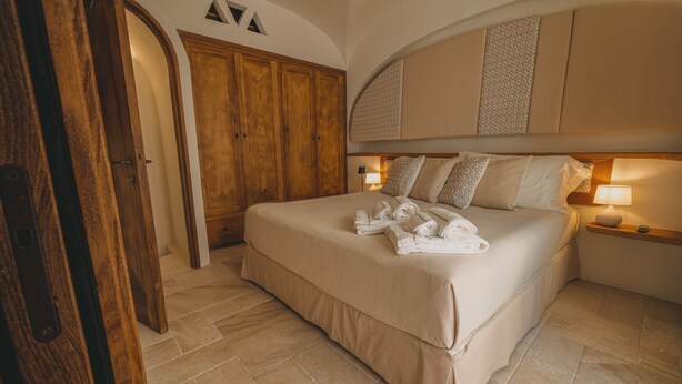 Ein Schlafzimmer mit einem großen Bett, einem Holzschrank und einem eingebauten Kopfteil mit Stauraum.