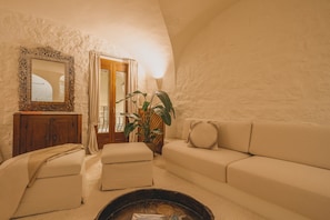 A cozy living room with a sofa, ottoman, and a fireplace. - Elite Collection - Olea: The Secret Roof (Olbia)
