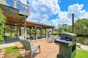An outdoor patio with a grill, chairs, and a view of a lake. - Scallop HQ: 3 Boat Docks and Free Golf Cart! (Homosassa)