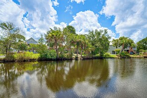 A calm lake with reflections of trees and houses, surrounded by greenery and clear skies. - Scallop HQ: 3 Boat Docks and Free Golf Cart! (Homosassa)