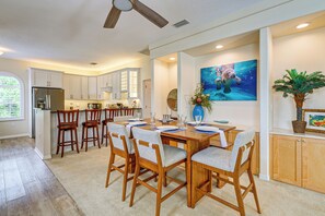 A modern kitchen with a dining area, wooden cabinets, and a ceiling fan. - Scallop HQ: 3 Boat Docks and Free Golf Cart! (Homosassa)