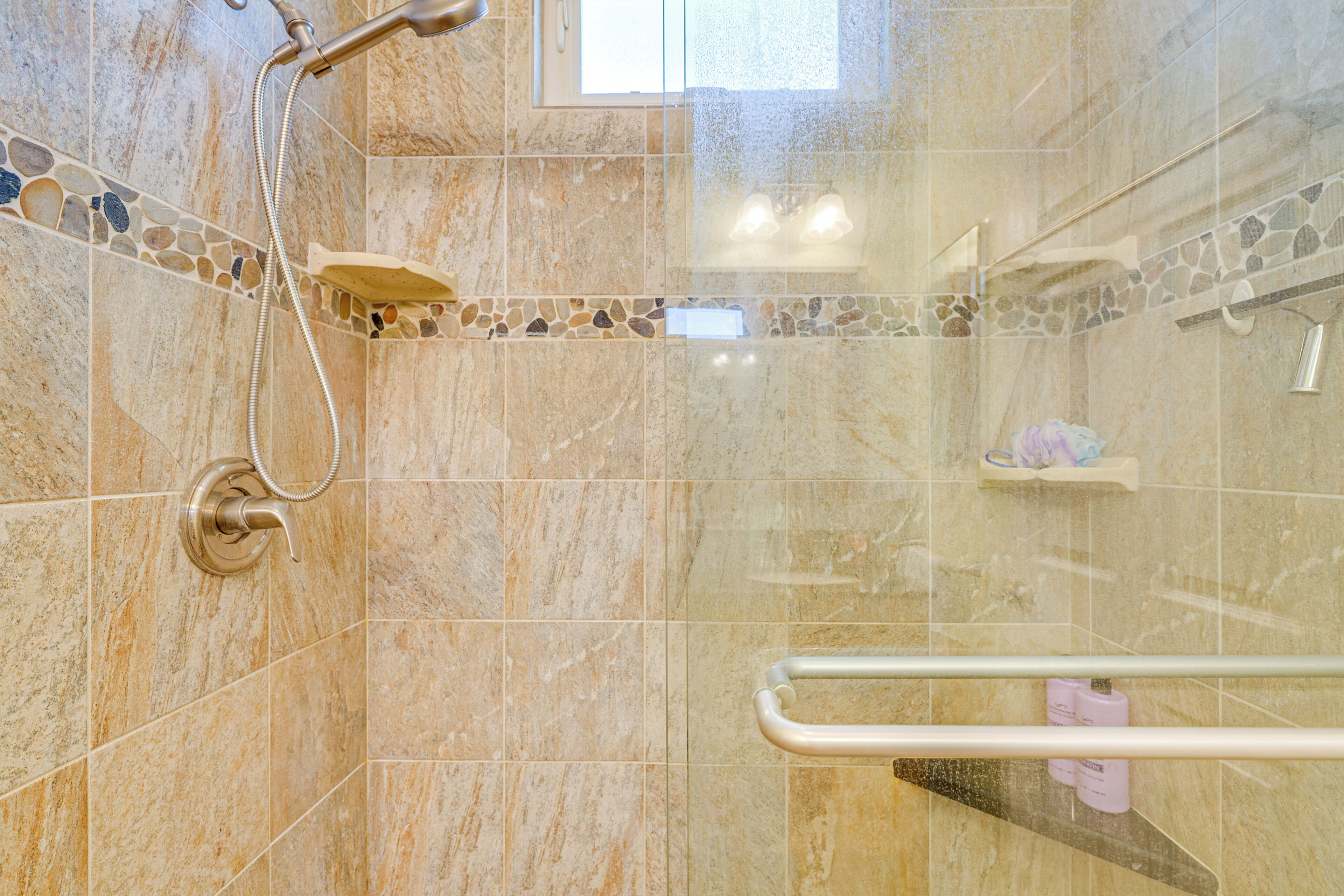 Een douche met douchekop, een douchecabine met glazen wanden en een handgreep.
