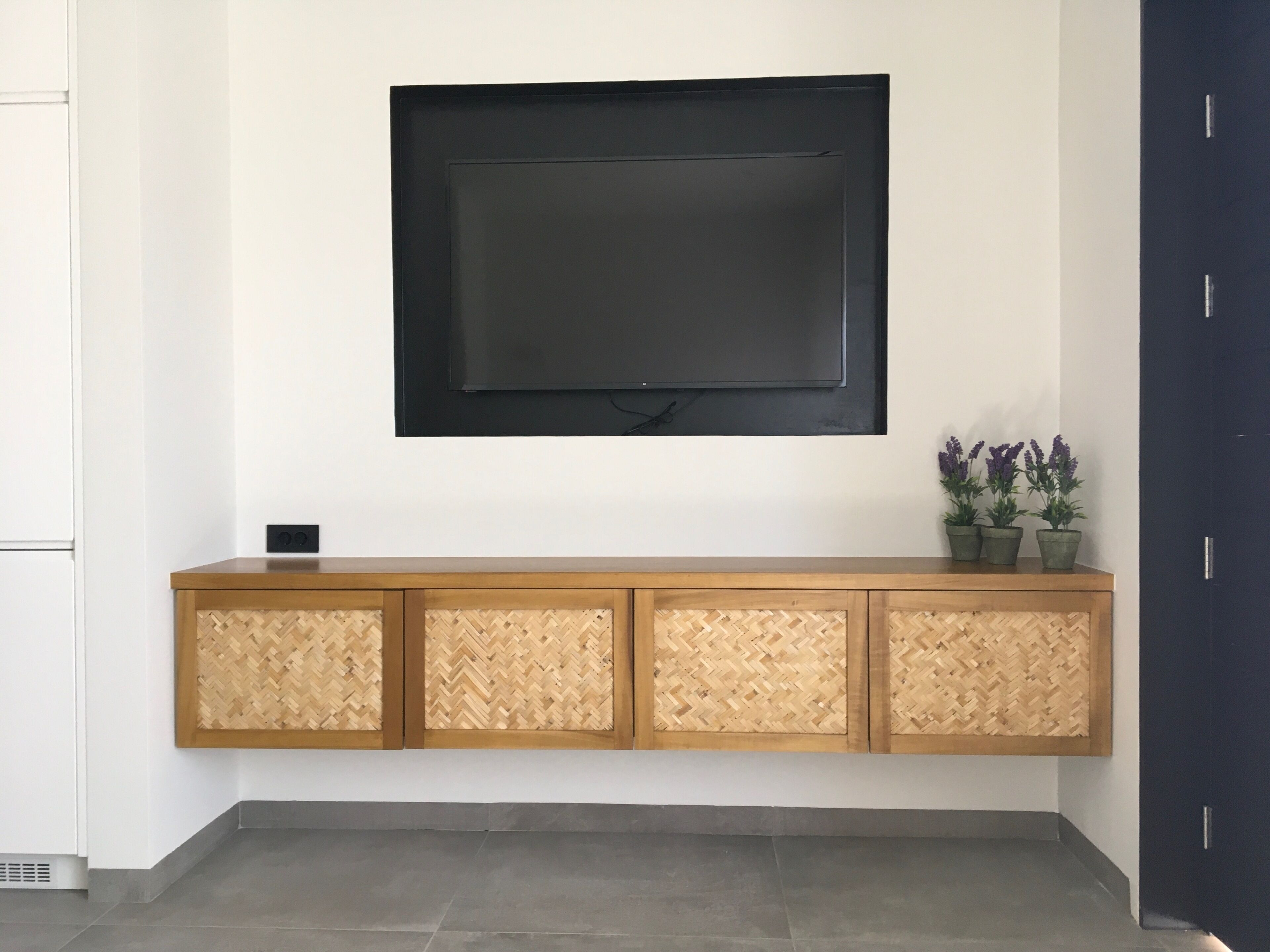 Un televisor de pantalla plana montado en la pared, sobre un mueble de madera con panel trasero tejido.