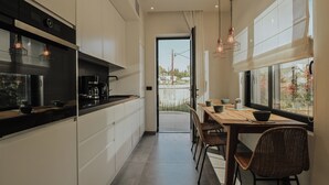 A modern kitchen with a dining area, large windows, and a view of the outside. - Elsa Modern Apartments (Pogonia)