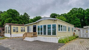 Ein Bungalow mit Veranda, überdachter Terrasse und kleinem Anbau für eine Garage.