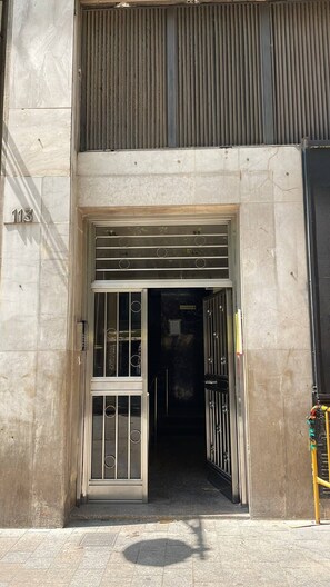 A building entrance with a metal gate, a sign above the door, and a number '113' on the wall. - Comfortable Studio Apartment | La Rambla 113, Downtown, Close to Everything (Cataluña)