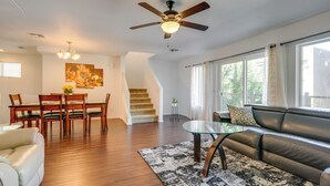 Ein geräumiges Wohnzimmer mit Essbereich, einer Couch, einem Glastisch und einem Deckenventilator.