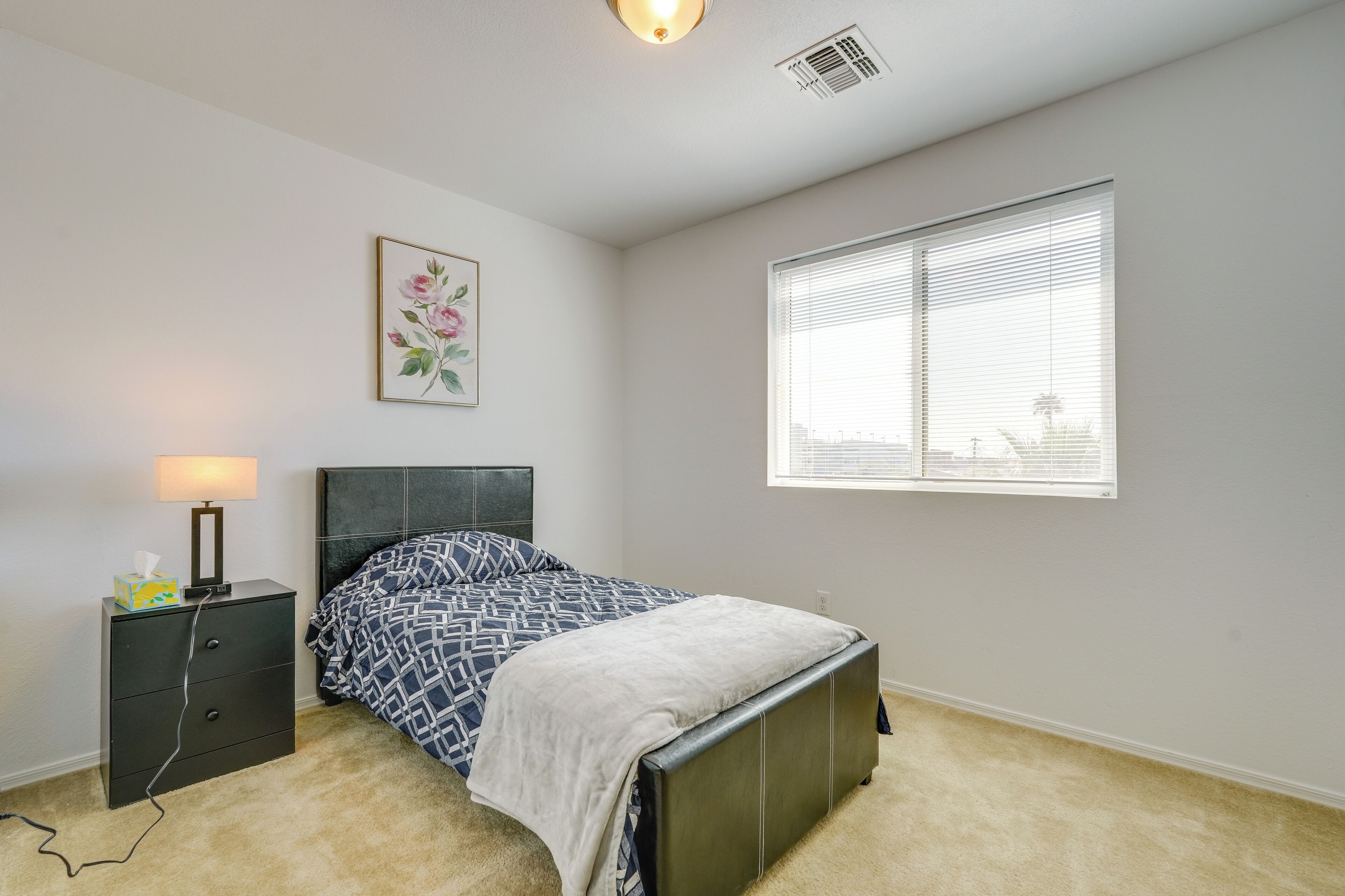A bedroom with a bed, bedside table, lamp, and window.