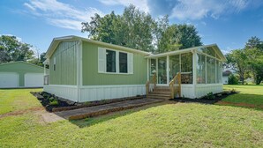 Ett enplanshus med en veranda framtill, ett takförsett område som fungerar som veranda och en liten trappa som leder upp till entrén.