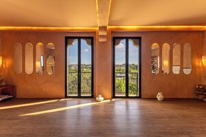 Amplia habitación con piso de madera, puertas grandes con paneles de vidrio y vista a zonas verdes.