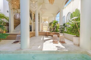 Un área de piscina con sillones de descanso, una escalera y ventanas amplias.
