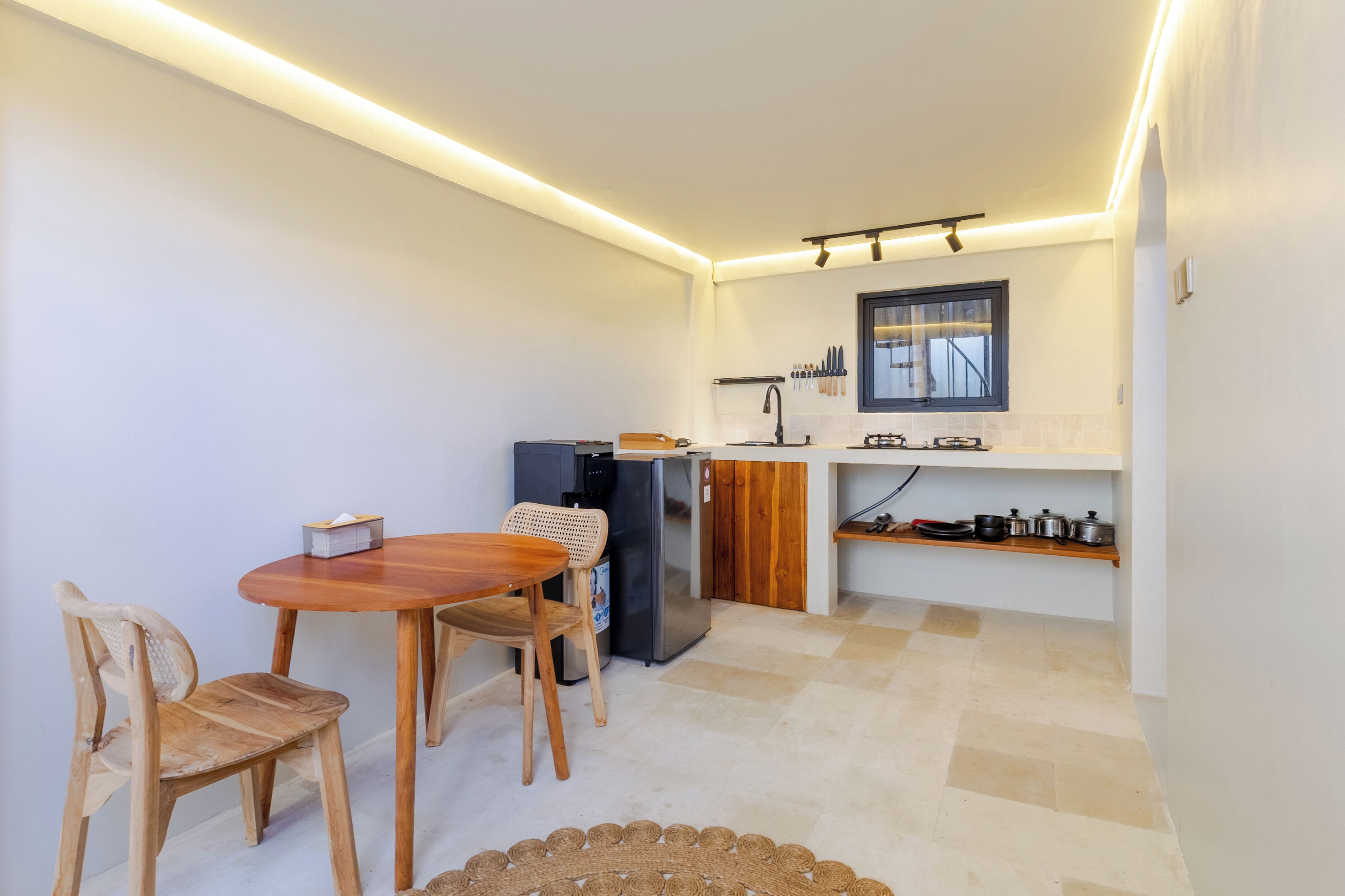 A compact kitchen with a dining table and chairs, a refrigerator, and a window with a view.