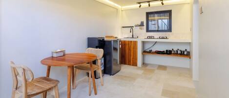 A compact kitchen with a dining table and chairs, a refrigerator, and a window with a view.