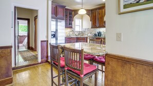 Una cocina con armarios de madera, encimera de mármol y una zona de comedor con sillas y una mesa.